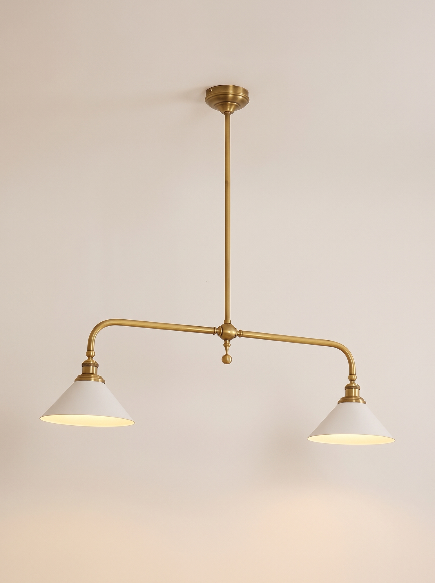 Thetford linear brass pendant lit warm on a soft off-white studio background