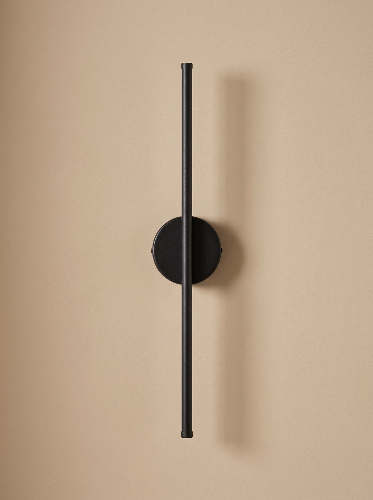 Tarn slim LED wall sconce in matte black on a warm sand backdrop