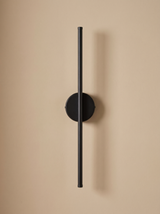 Tarn slim LED wall sconce in matte black on a warm sand backdrop