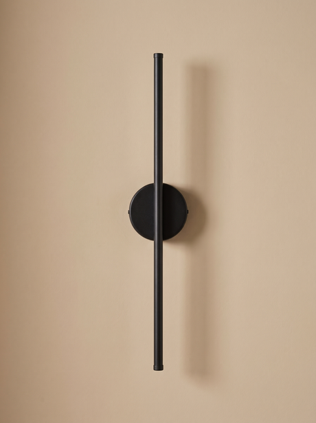 Tarn slim LED wall sconce in matte black on a warm sand backdrop