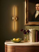 Lifestyle: brass Tarn wall sconce glowing on an olive wall beside a gilt-framed portrait, above a walnut dresser