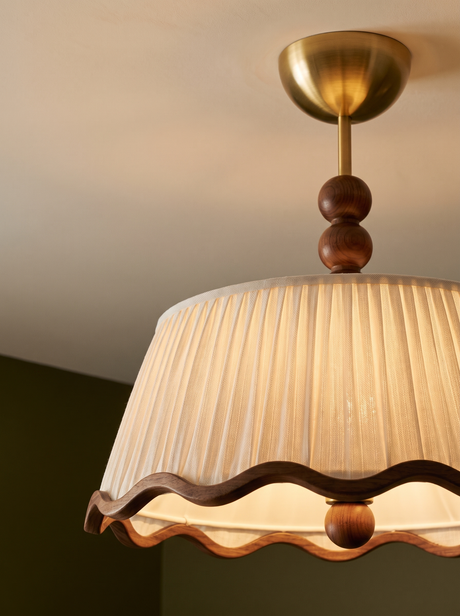 Lifestyle: close-up of Odette's pleated shade, wavy walnut trim and wood beads, lit