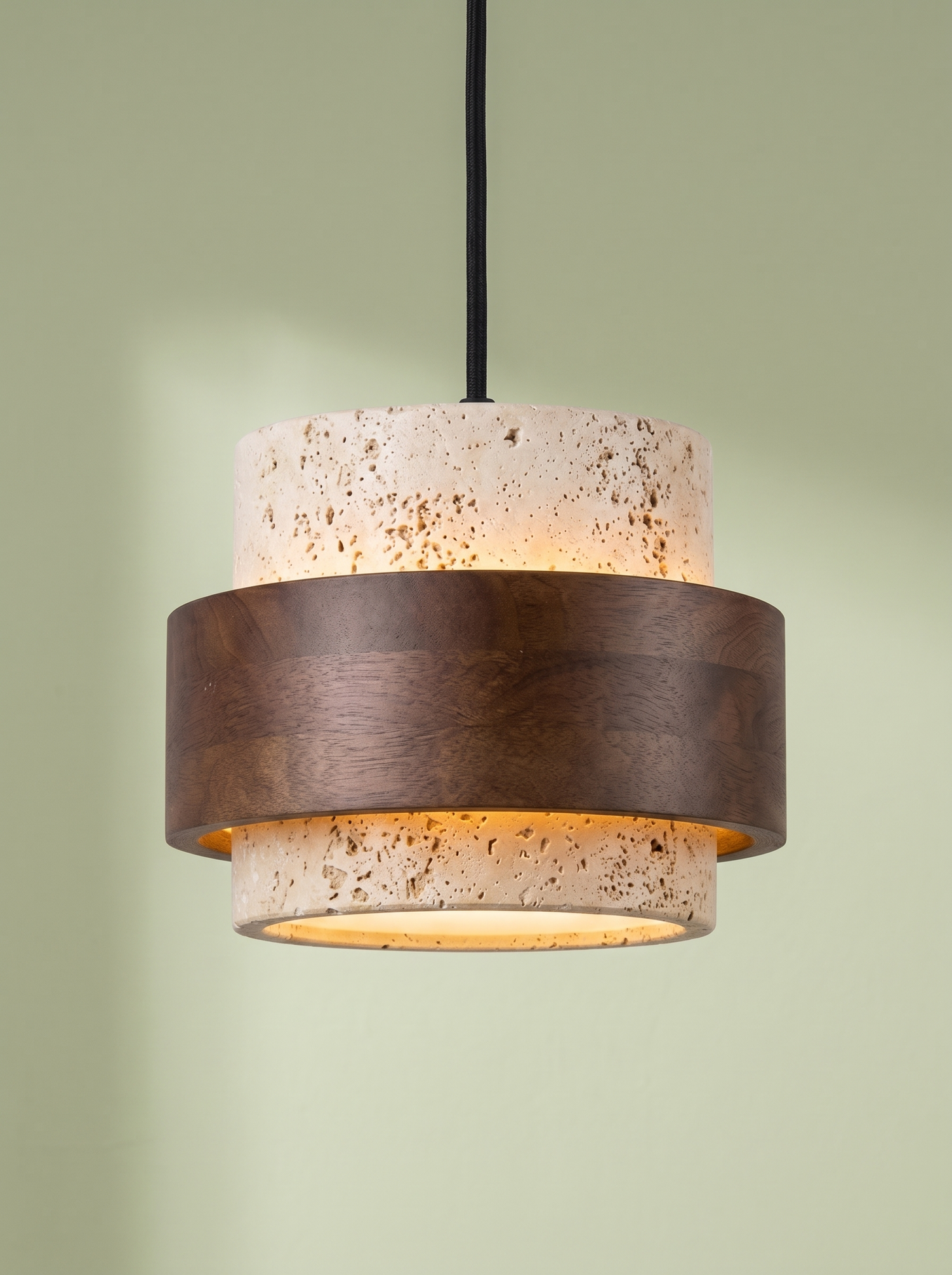 Rune travertine and walnut pendant light glowing on a pistachio green backdrop