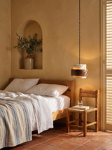 Lifestyle: Rune pendant hung low as a bedside light in a sunlit Mediterranean bedroom, shown to scale