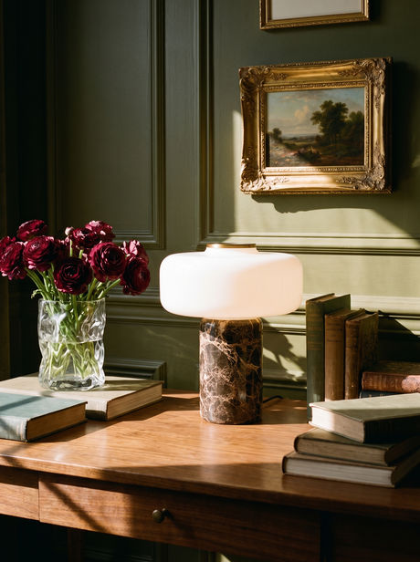 Lifestyle: Dessa marble table lamp glowing on a walnut desk in an olive library