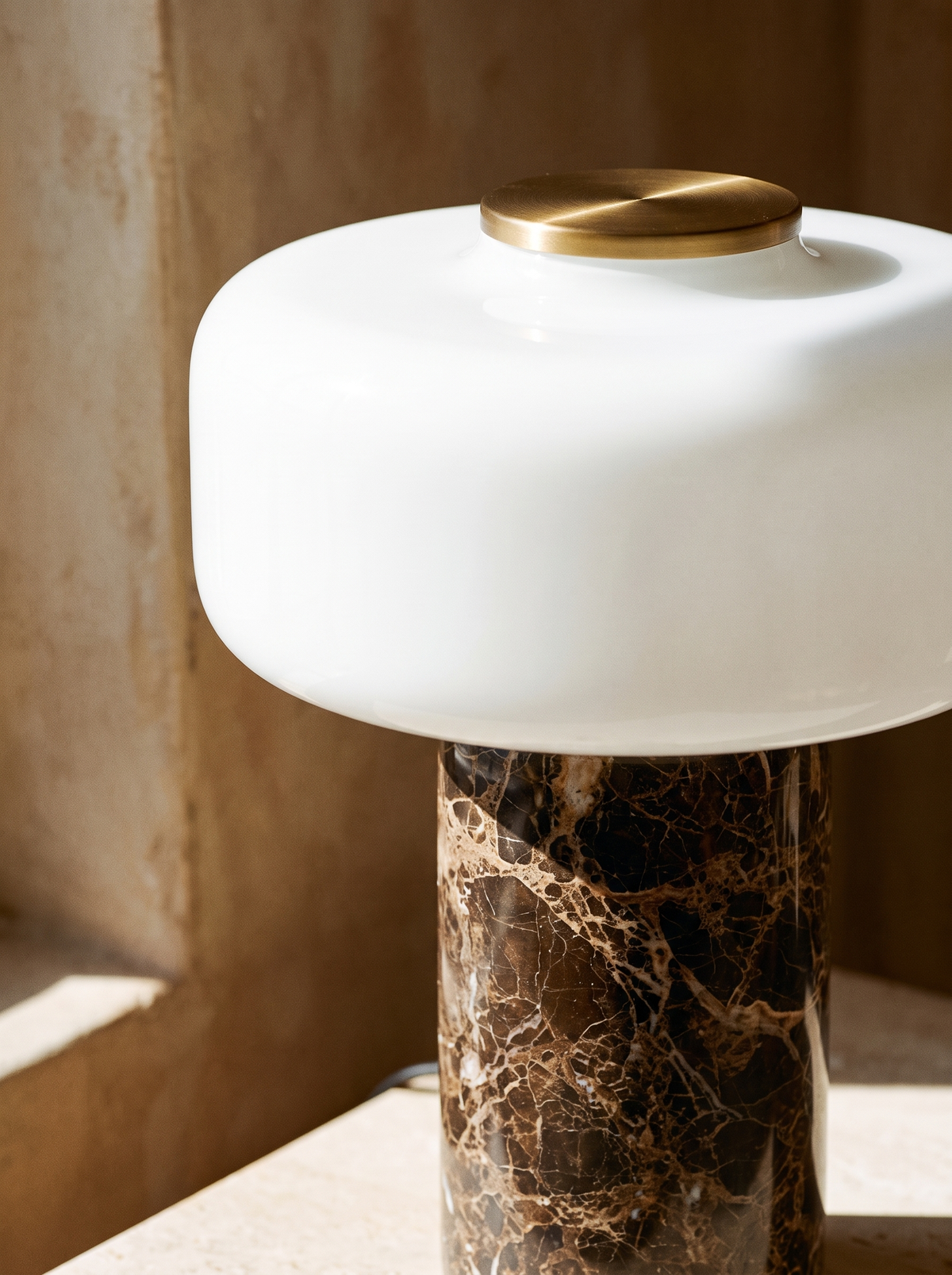 Lifestyle: close-up of Dessa's marble base, opal glass shade and brass top, lit