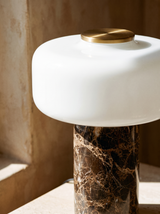 Lifestyle: close-up of Dessa's marble base, opal glass shade and brass top, lit