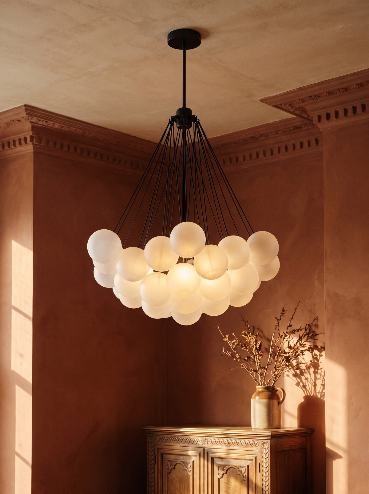 Perle chandelier in black with frosted glass globes in a terracotta plaster corner