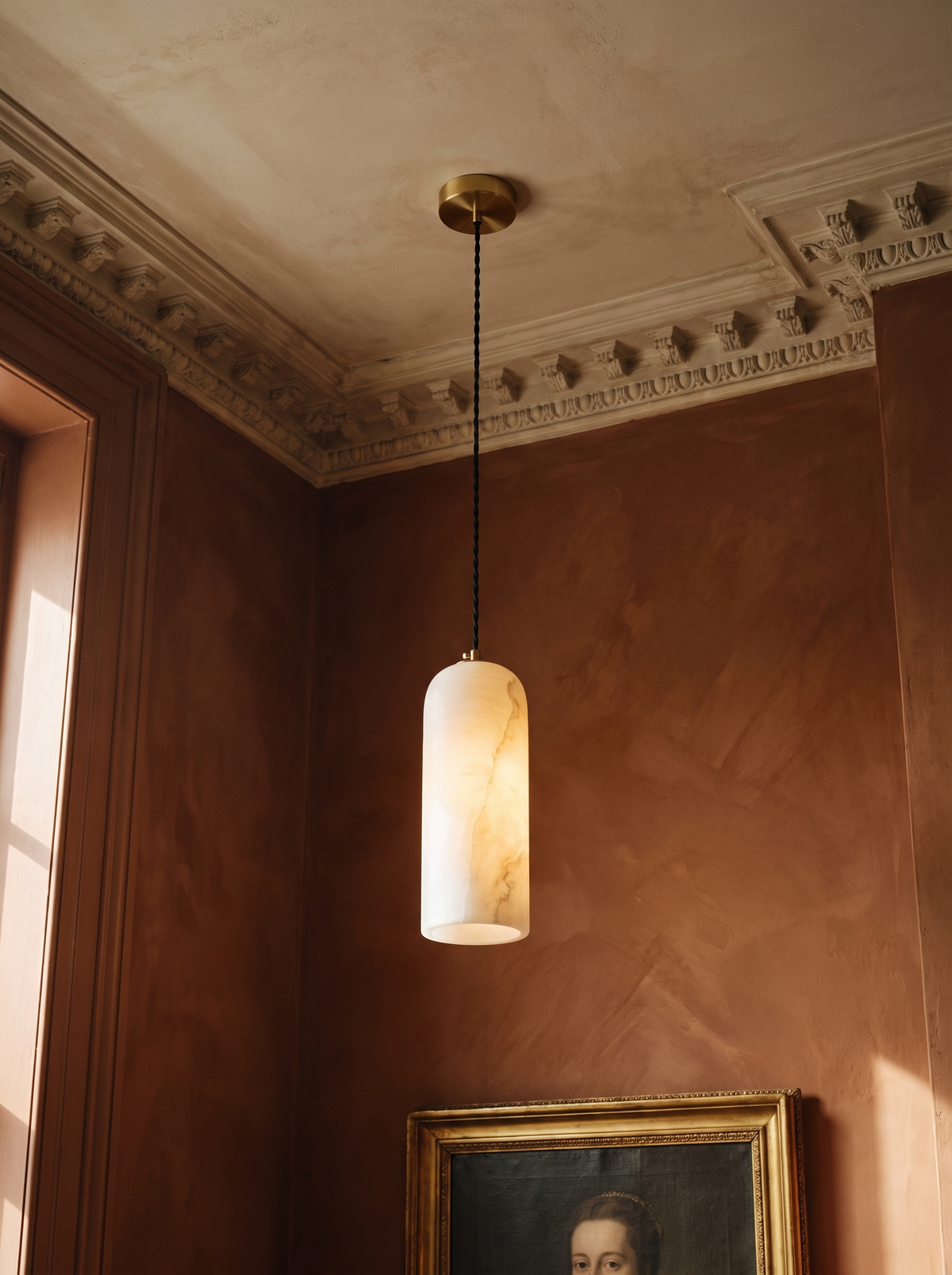 Sola alabaster pendant light in brass hanging in a sienna plaster corner