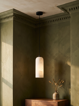 Sola alabaster pendant light in black hanging in an olive plaster corner