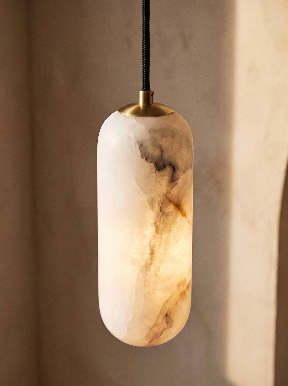 Lifestyle: close-up of Sola's veined alabaster cylinder, brass cap and braided cord