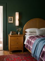 Lifestyle: Aurelie alabaster sconce beside a bed in a forest-green bedroom