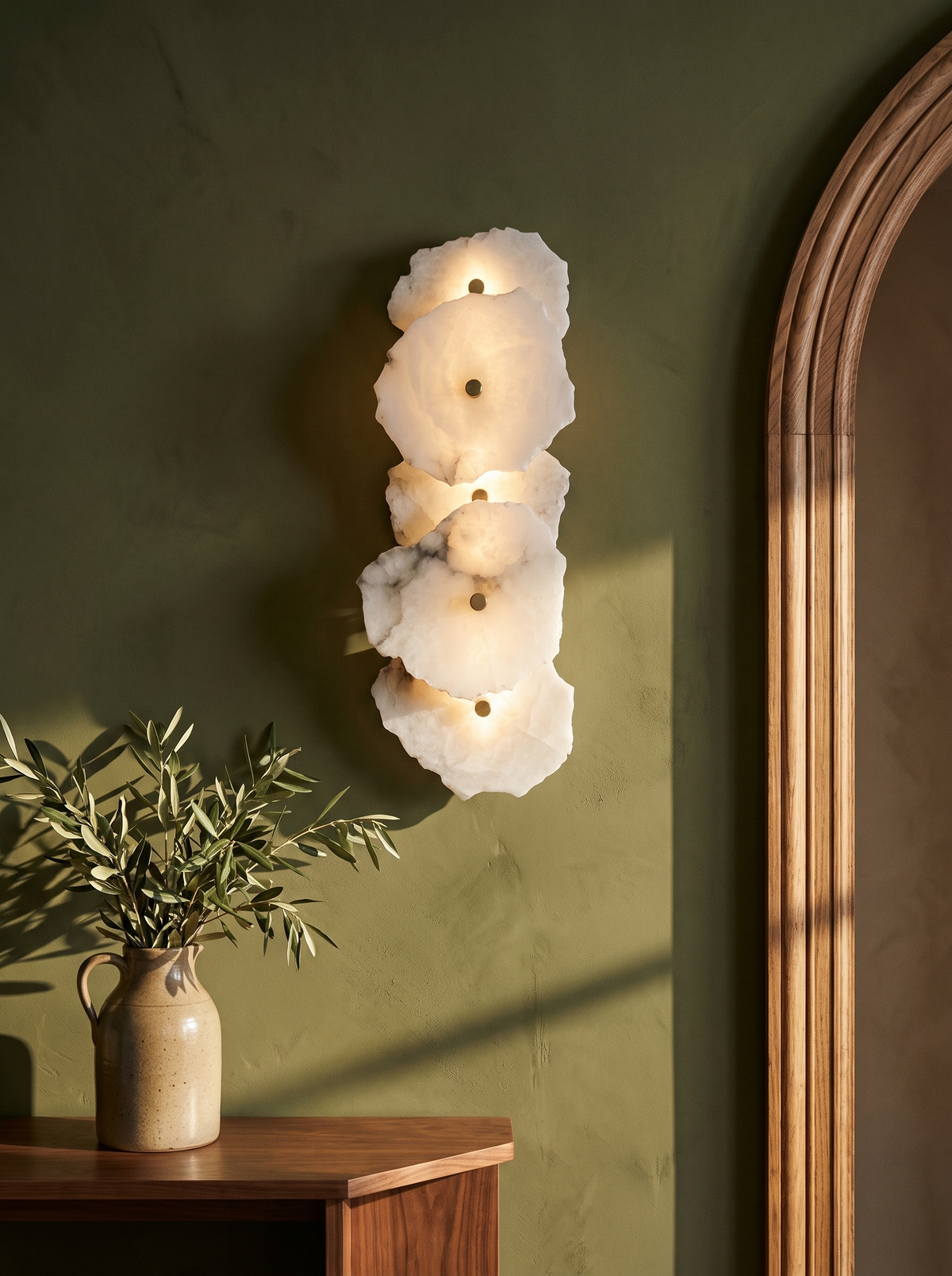 Seren alabaster wall sconce in gold and white on an olive plaster wall
