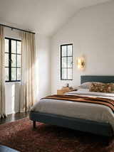 Lifestyle: Romy alabaster sconce beside a bed in a vaulted plaster bedroom