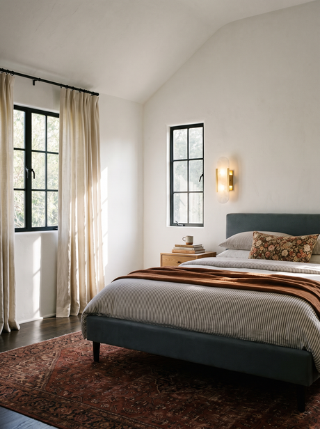 Lifestyle: Romy alabaster sconce beside a bed in a vaulted plaster bedroom