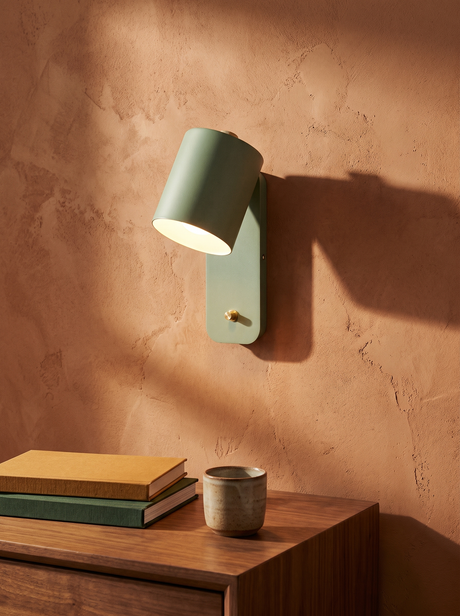 Tate swivel cylinder wall lamp in sage green on a clay plaster wall