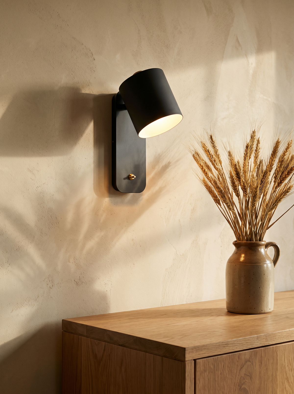 Tate swivel cylinder wall lamp in black on an ochre plaster wall