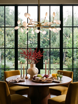 Lifestyle: Luce firefly chandelier over a round walnut table in a garden-view dining room