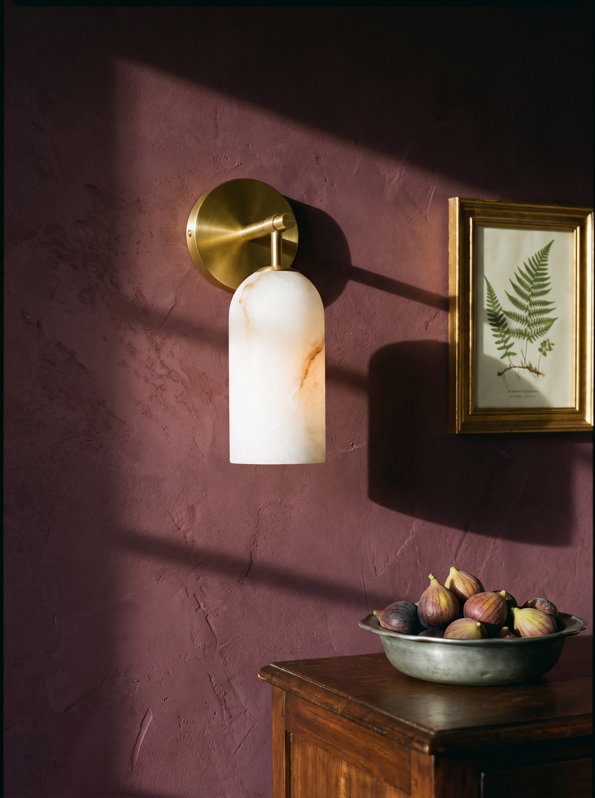 Pilar alabaster wall sconce in gold on a mulberry plaster wall