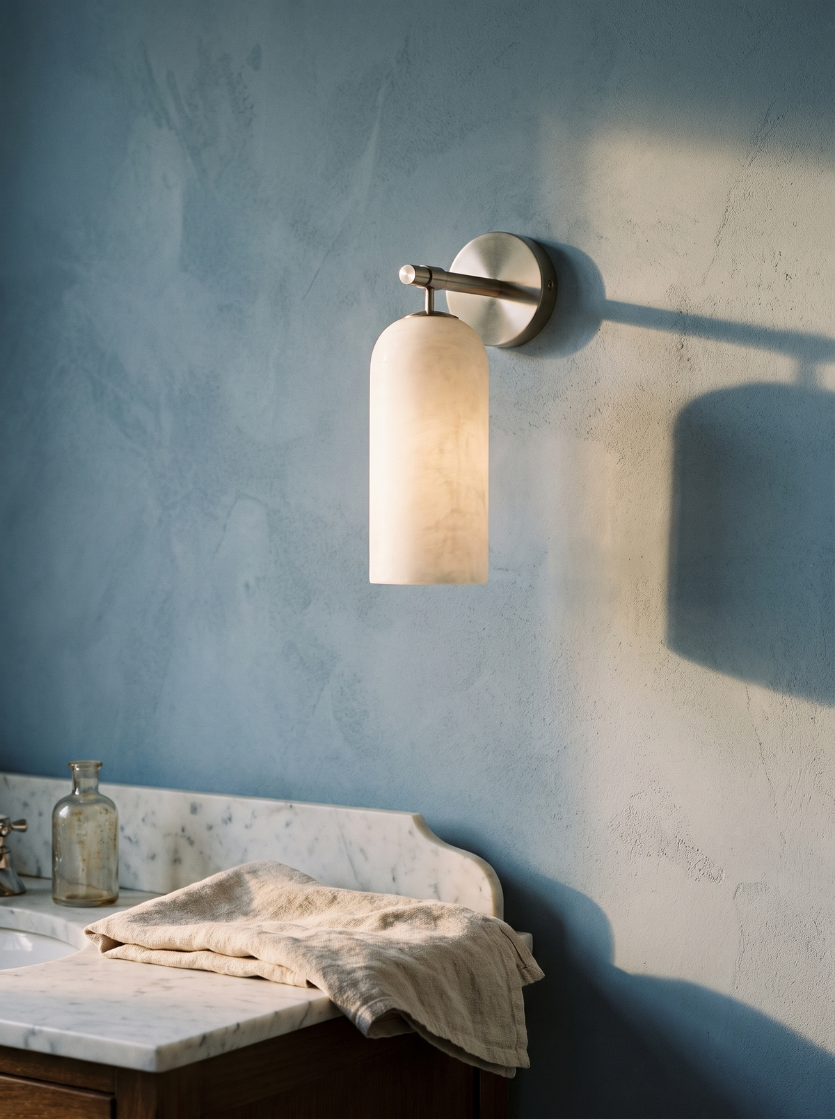 Pilar alabaster wall sconce in nickel on a powder-blue plaster wall