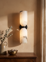 Nyx up-and-down alabaster wall sconce in black on a caramel plaster wall
