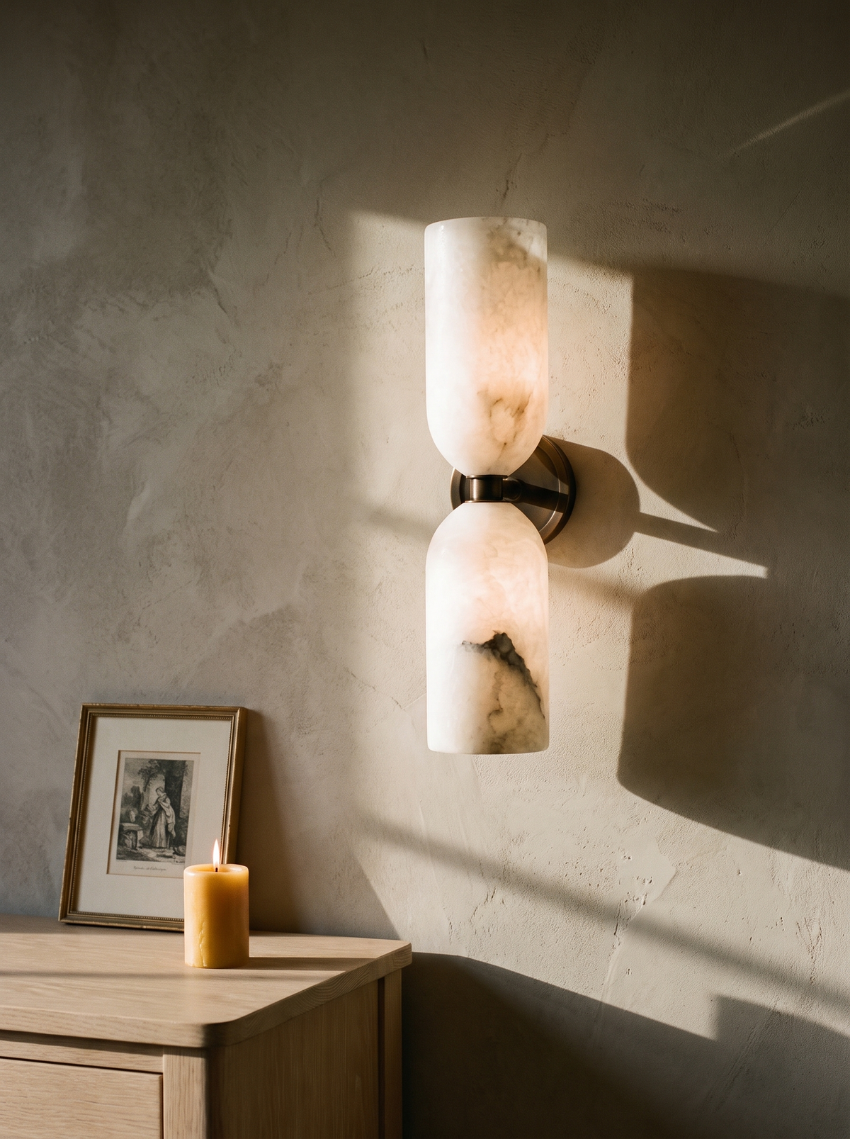 Nyx up-and-down alabaster wall sconce in bronze on a greige plaster wall