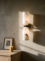 Nyx up-and-down alabaster wall sconce in bronze on a greige plaster wall