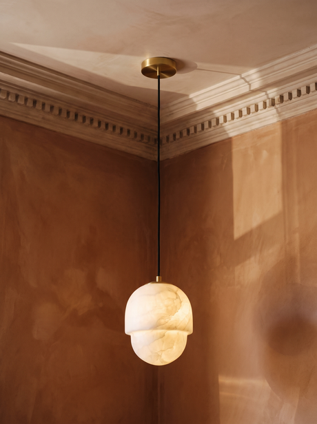 Oaklee acorn alabaster pendant light in brass hanging in a sienna plaster-moulded corner