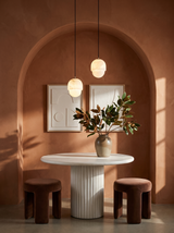 Lifestyle: a pair of Oaklee acorn alabaster pendants above a fluted table in a terracotta dining alcove