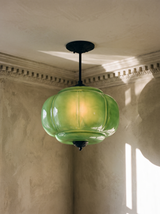 Ivy green glass semi-flush ceiling light in black hanging in a plaster-moulded corner