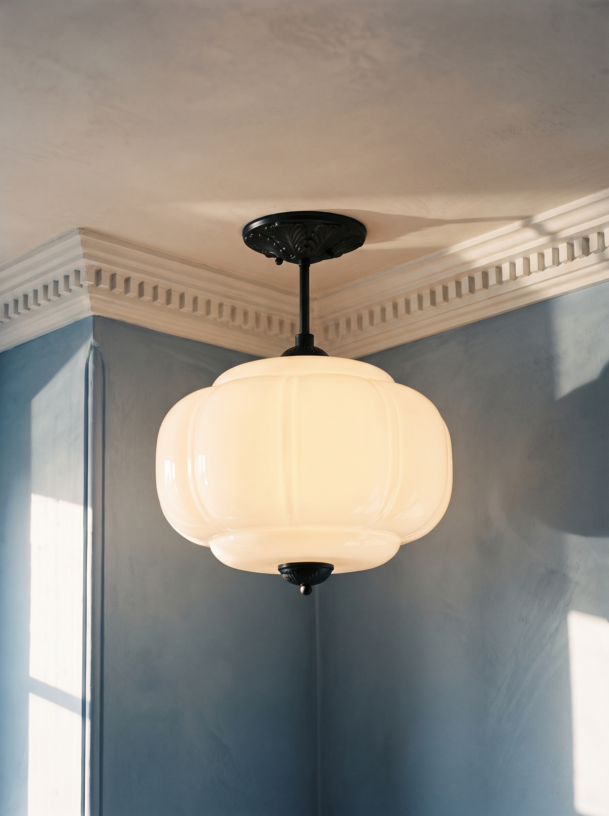 Ivy white glass semi-flush ceiling light in black hanging in a plaster-moulded corner