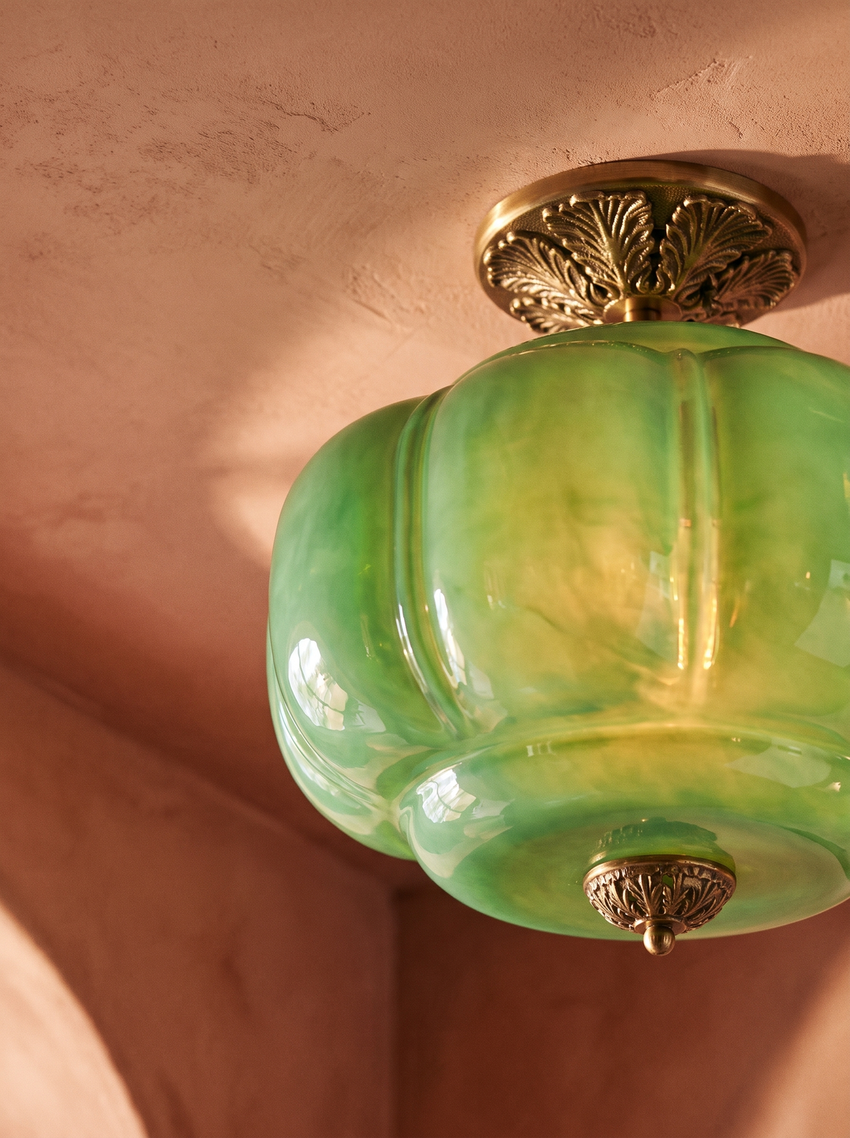 Lifestyle: close-up of Ivy's ribbed green glass and ornate brass canopy, lit
