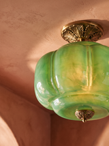 Lifestyle: close-up of Ivy's ribbed green glass and ornate brass canopy, lit