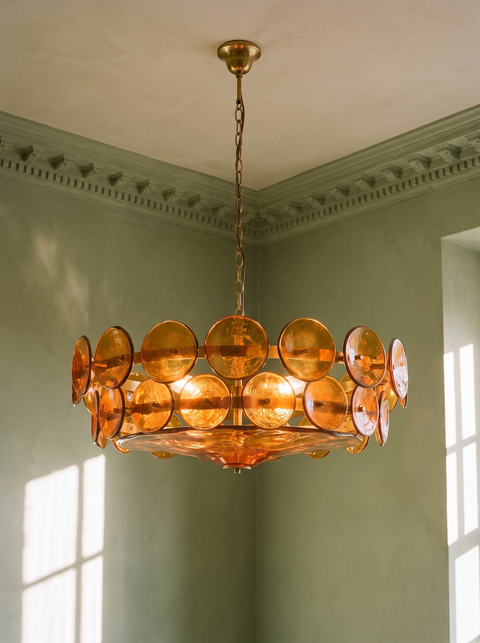Soleil amber glass disc chandelier hanging in a plaster-moulded corner
