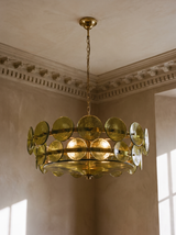 Soleil olive-green glass disc chandelier hanging in a plaster-moulded corner
