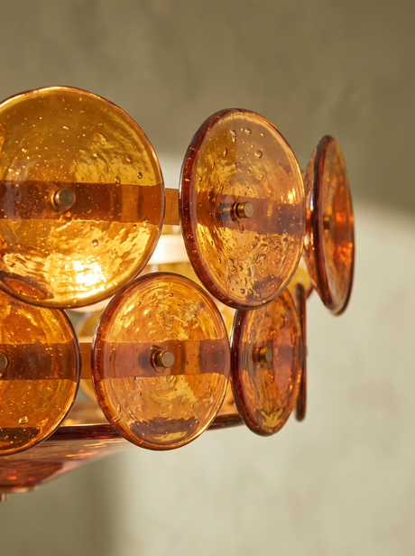 Lifestyle: close-up of Soleil's hand-cast amber glass discs, lit