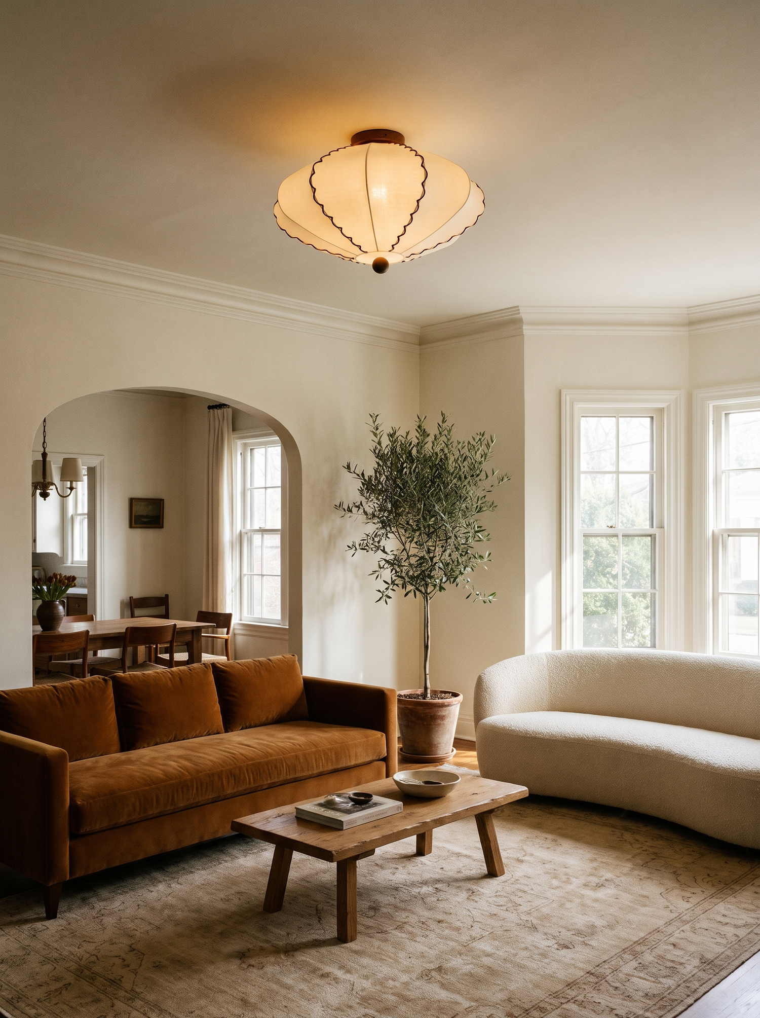 Lifestyle: Bonnie scalloped ceiling light in a living room with a cognac velvet sofa, showing its size