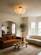 Lifestyle: Bonnie scalloped ceiling light in a living room with a cognac velvet sofa, showing its size