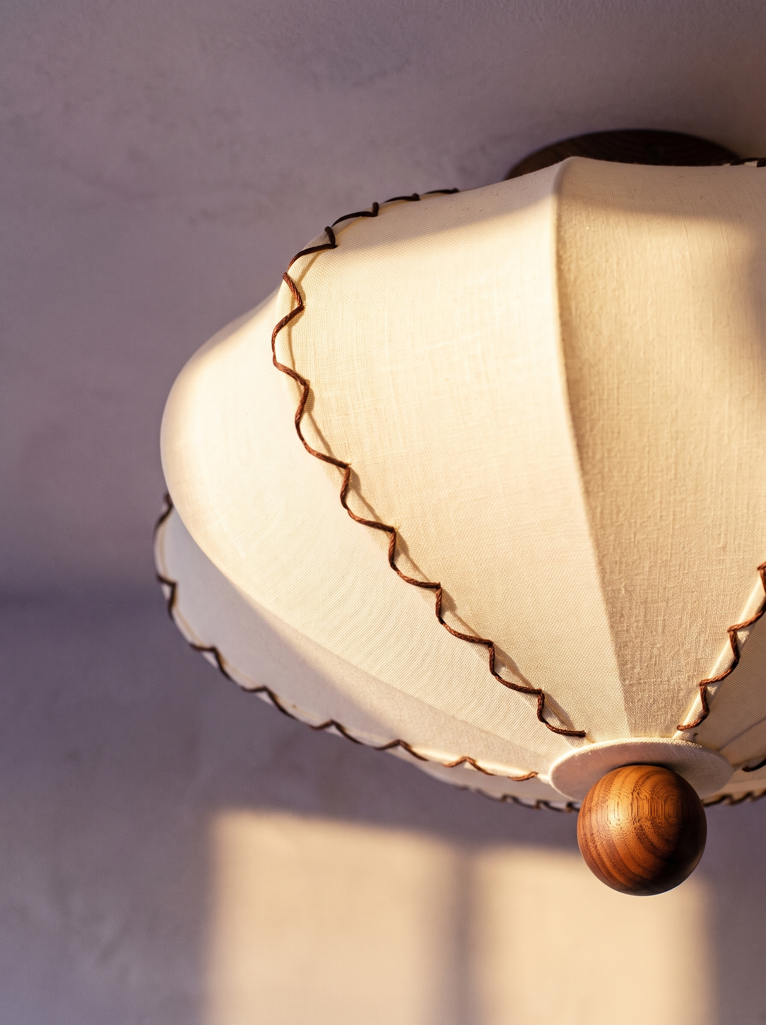 Lifestyle: close-up of Bonnie's scalloped fabric, contrast piping and walnut finial, lit