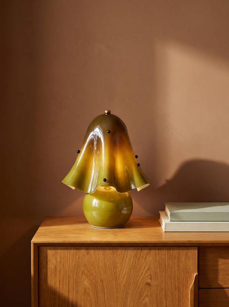 Petal green glass flower table lamp on an oak console against a warm plaster wall