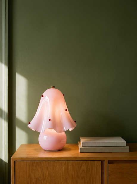 Petal pink glass flower table lamp on an oak console against a warm plaster wall