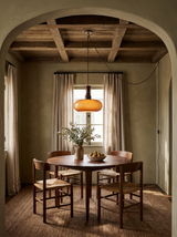 Lifestyle: Toffee caramel glass pendant over a round walnut table in an olive plaster dining room