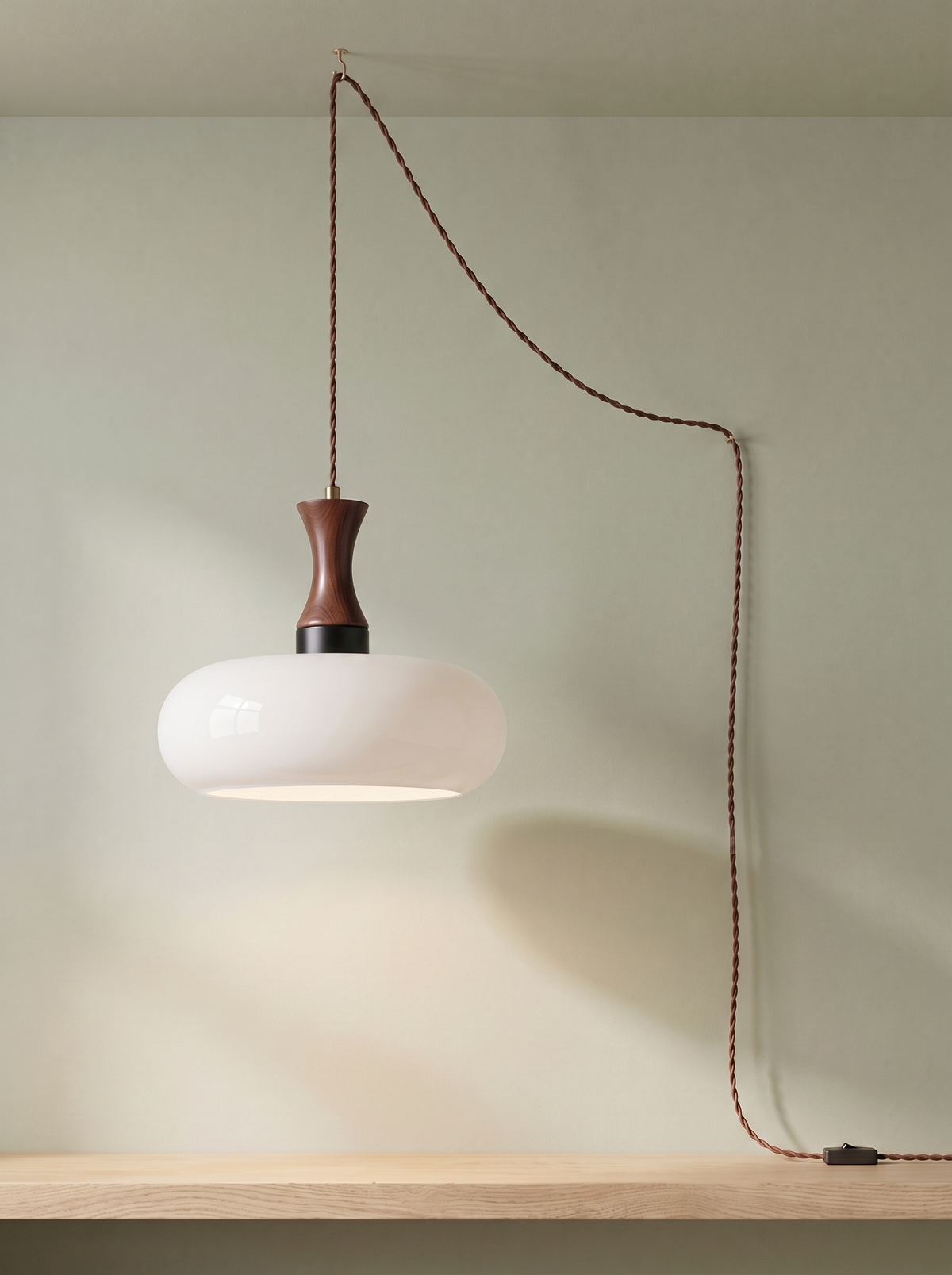 Toffee plug-in glass pendant light in milky white on a sage green backdrop
