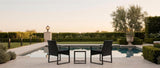 Nero bistro set on a poolside travertine terrace at dusk with coordinating lantern and path lights — lifestyle