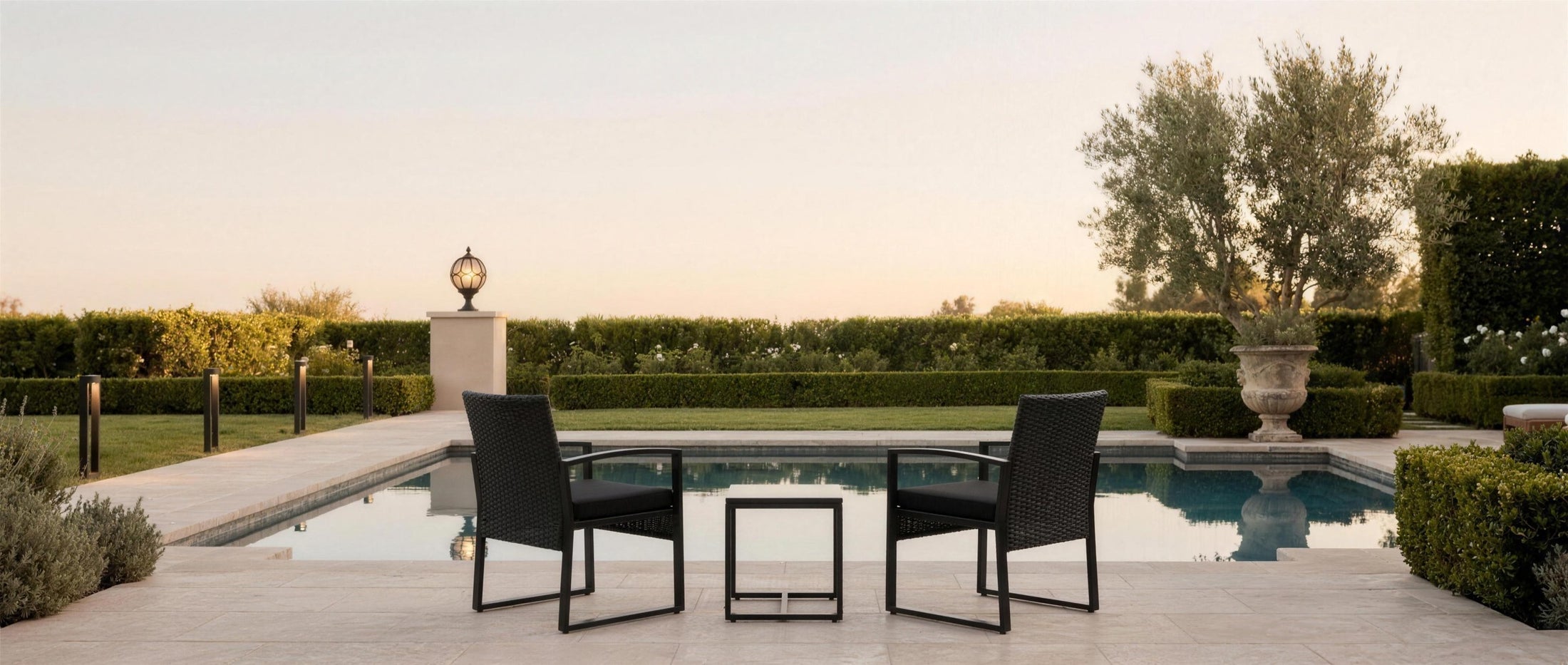Nero bistro set on a poolside travertine terrace at dusk with coordinating lantern and path lights — lifestyle