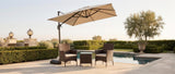 Sabbia wicker set under a beige umbrella on a poolside travertine terrace at golden hour — lifestyle