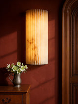 Clio large ribbed alabaster wall sconce on an oxblood plaster wall