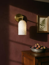 Pilar hand-faceted alabaster wall sconce in gold on a mulberry plaster wall