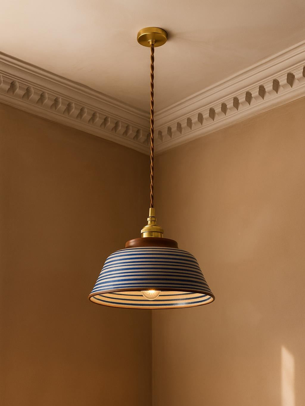 Delft blue ring ceramic pendant light hanging in a plaster-moulded corner