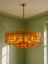 Soleil 31.5-inch amber glass disc chandelier hanging in a plaster-moulded corner